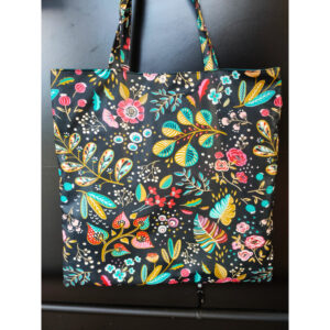 Tote-bag imperméable noir motifs fleurs avec une poche zippée et un mousqueton accroche-clé. Il se ferme par une pression.