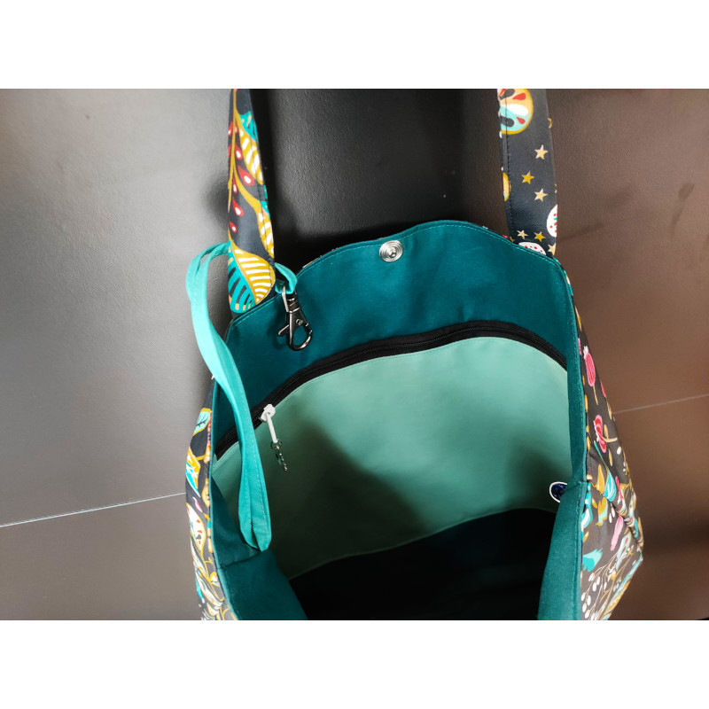 Tote-bag imperméable noir motifs fleurs avec une poche zippée et un mousqueton accroche-clé. Il se ferme par une pression. vue de l'intérieur