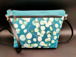 Sac bandoulière vert eucalyptus Les sacs de Cath Sac bandoulière vert eucalyptus en velours vert avec poche extérieure zippée en tissu motifs eucalyptus. Les sacs de Cath