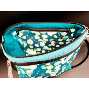 Sac bandoulière vert eucalyptus en velours vert avec poche extérieure zippée en tissu motifs eucalyptus. Photo fr l'intérieur qui comprend une poche zippée